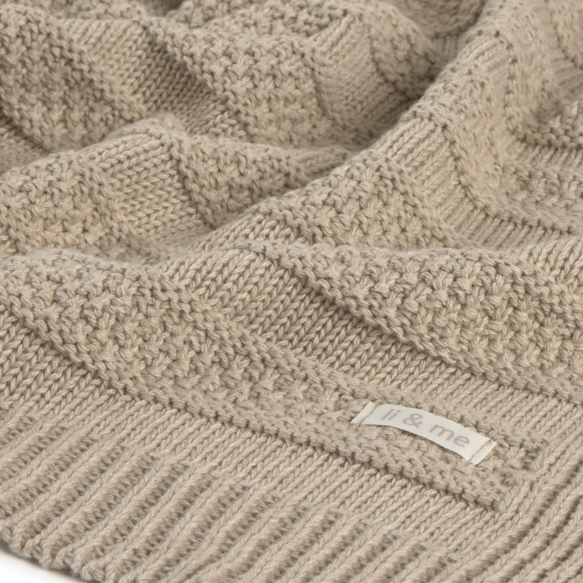 Pano de malha bege com padrões variados e etiqueta li & me