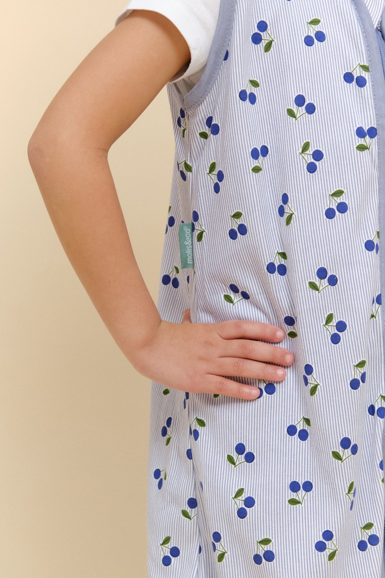 Detalhe de vestido infantil com padrão de cerejas azuis e riscas finas azuis