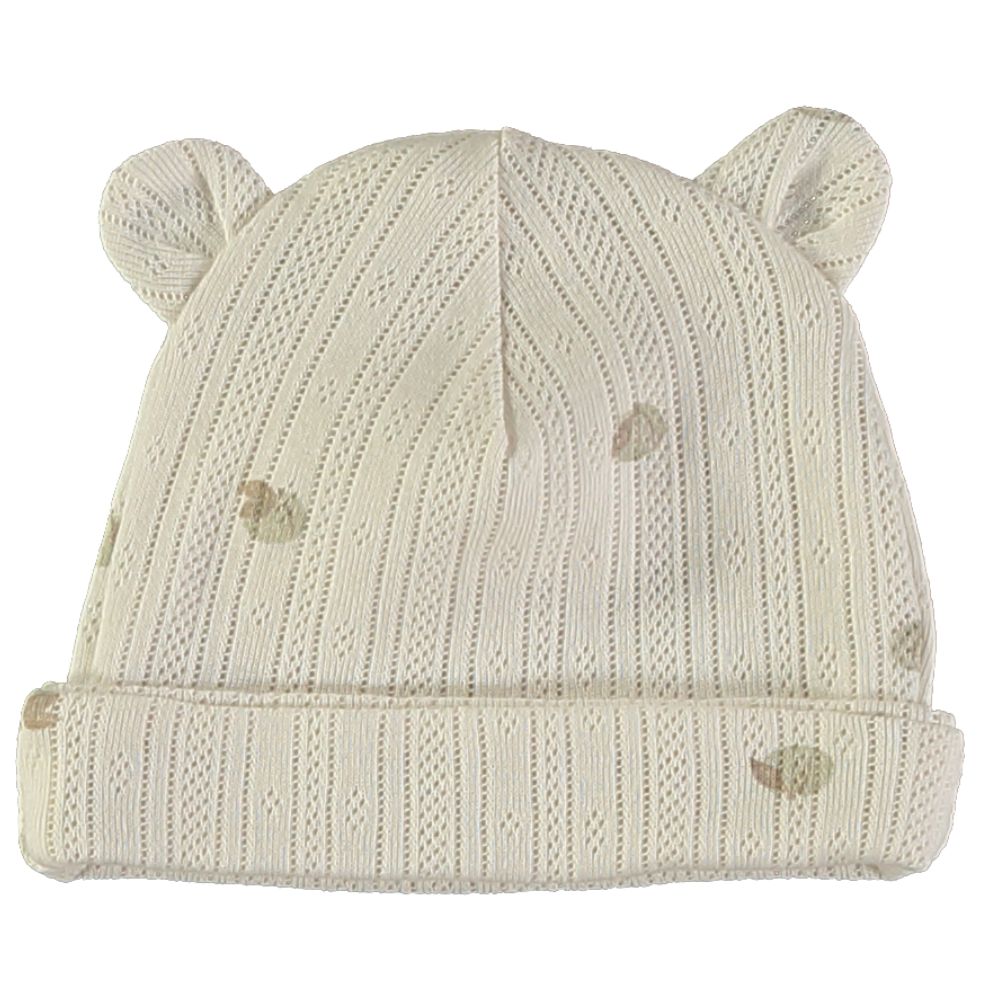Gorro de malha bege claro com orelhas bordadas e padrão de pontos.