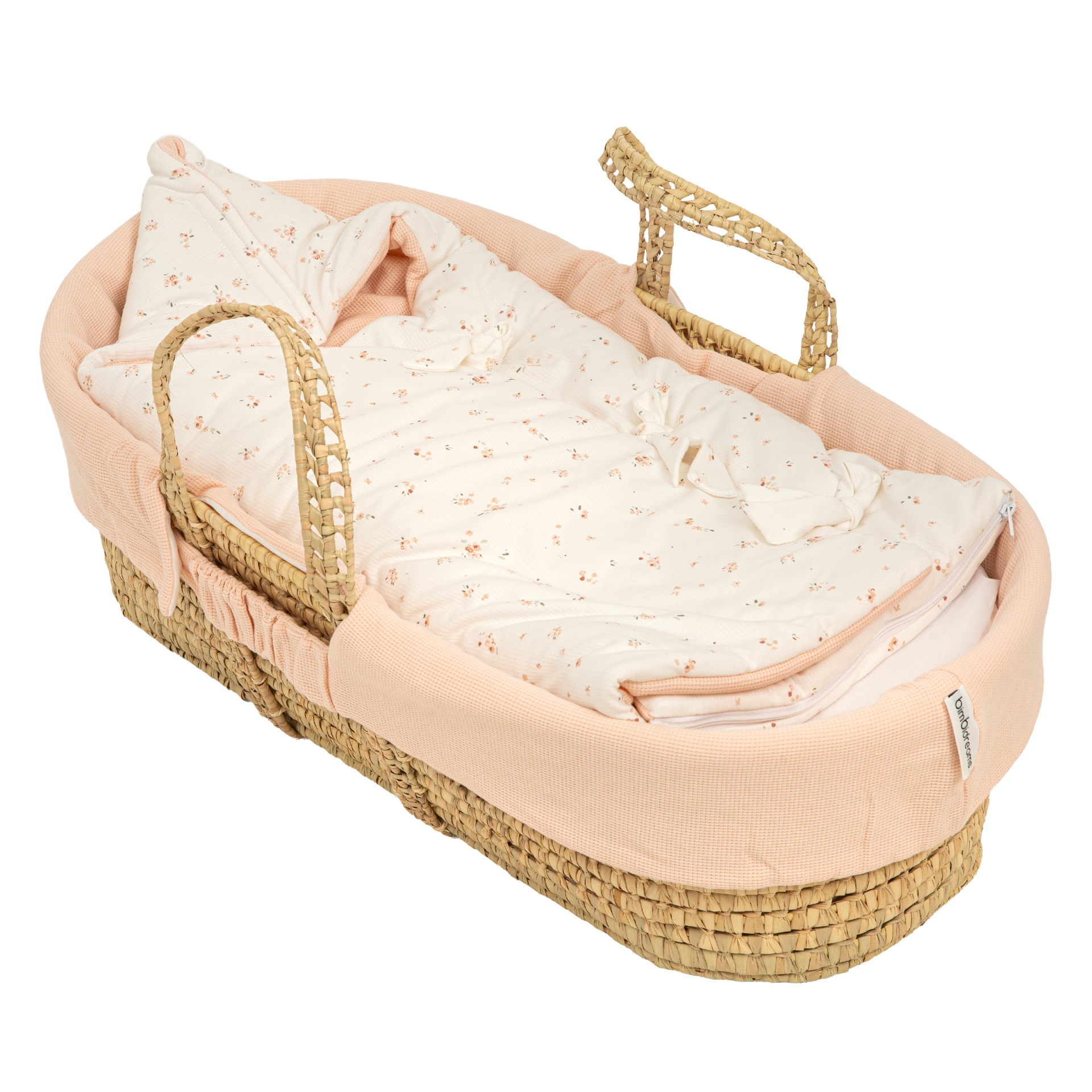 Cesta de bebé trançada com interior rosa e saco de dormir branco com flores pequenas.