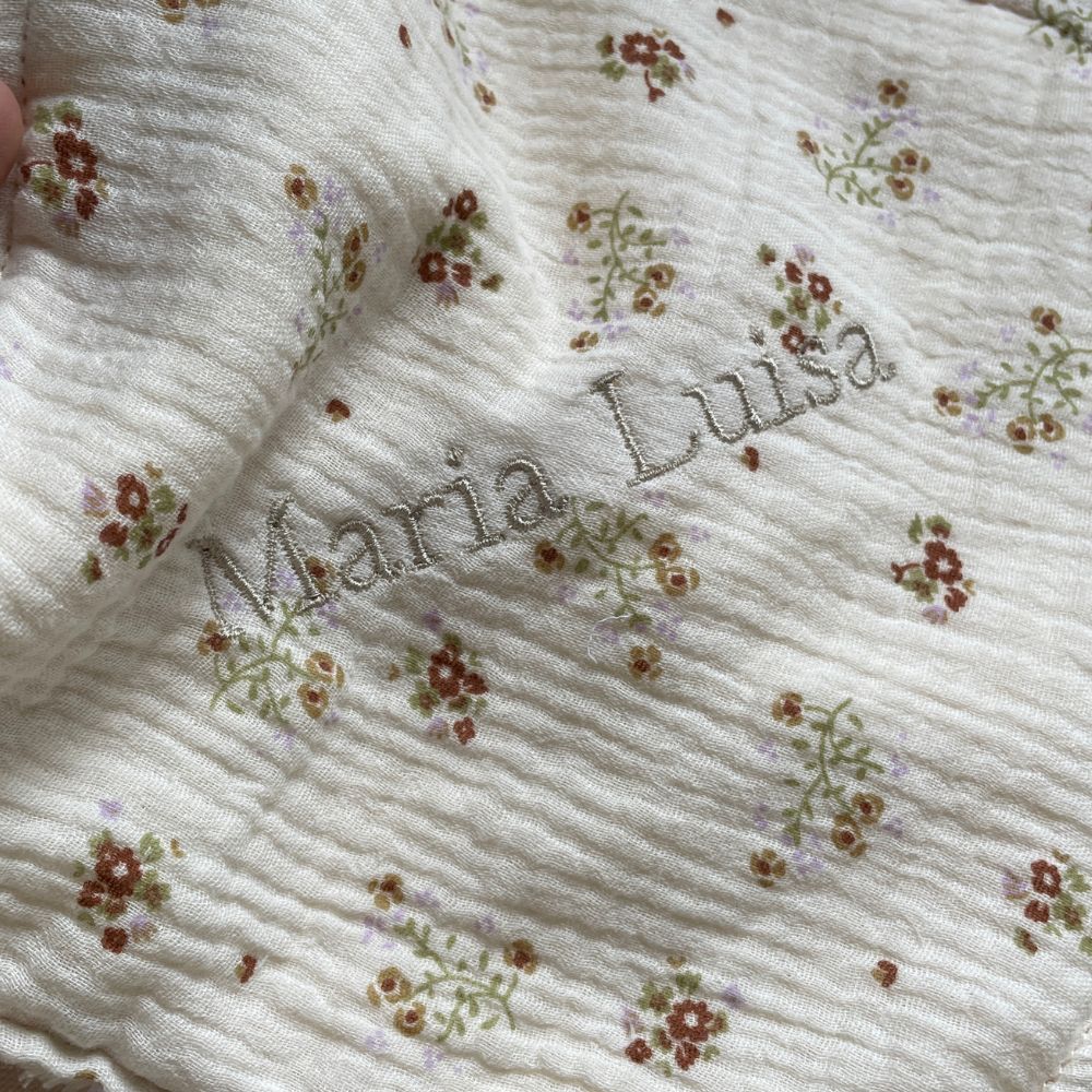 Pano branco frisado com flores castanhas e bordado com nome Maria Luísa