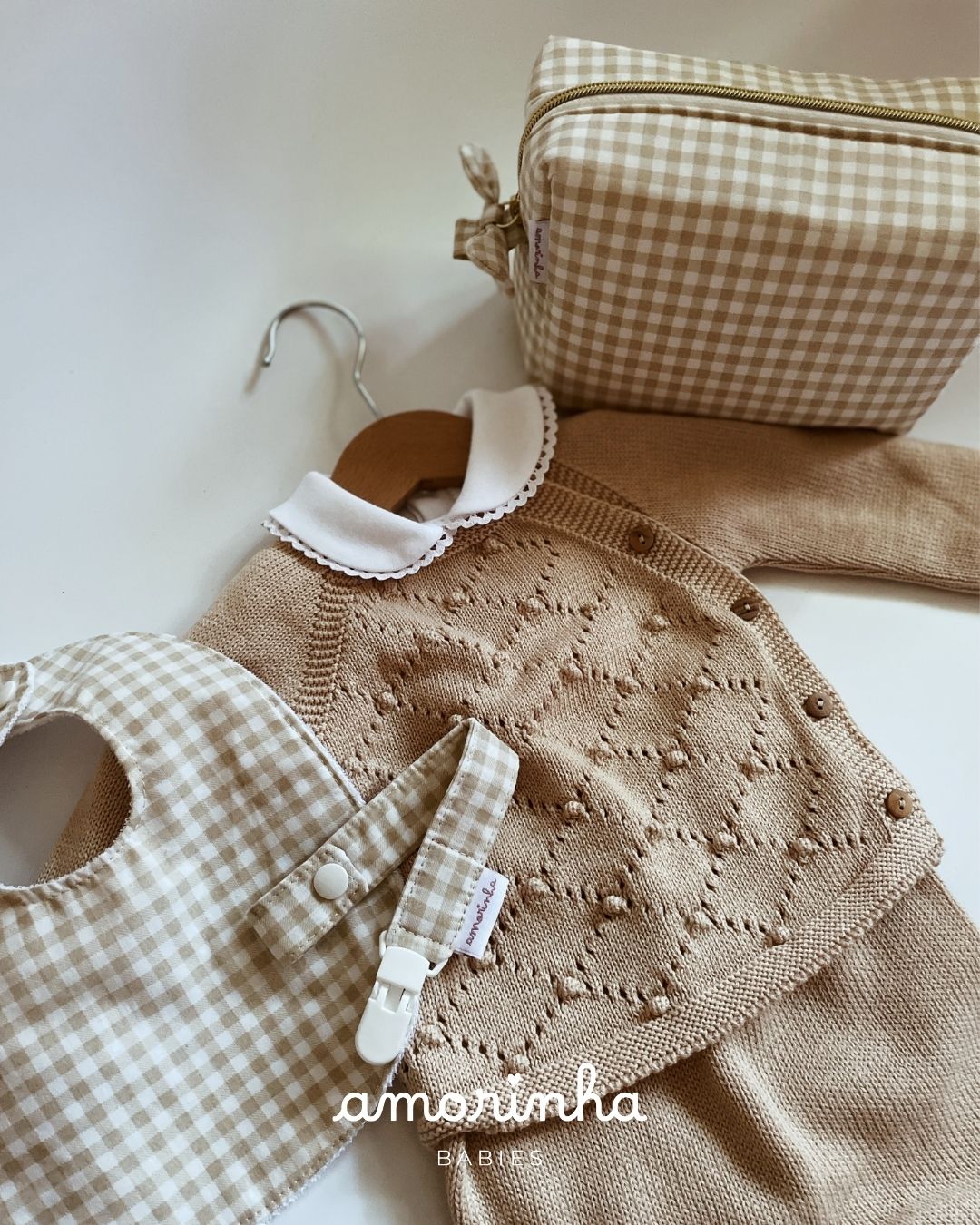 Conjunto de roupa e acessórios para bebé em tons bege e branco com padrão vichy e gola em malha