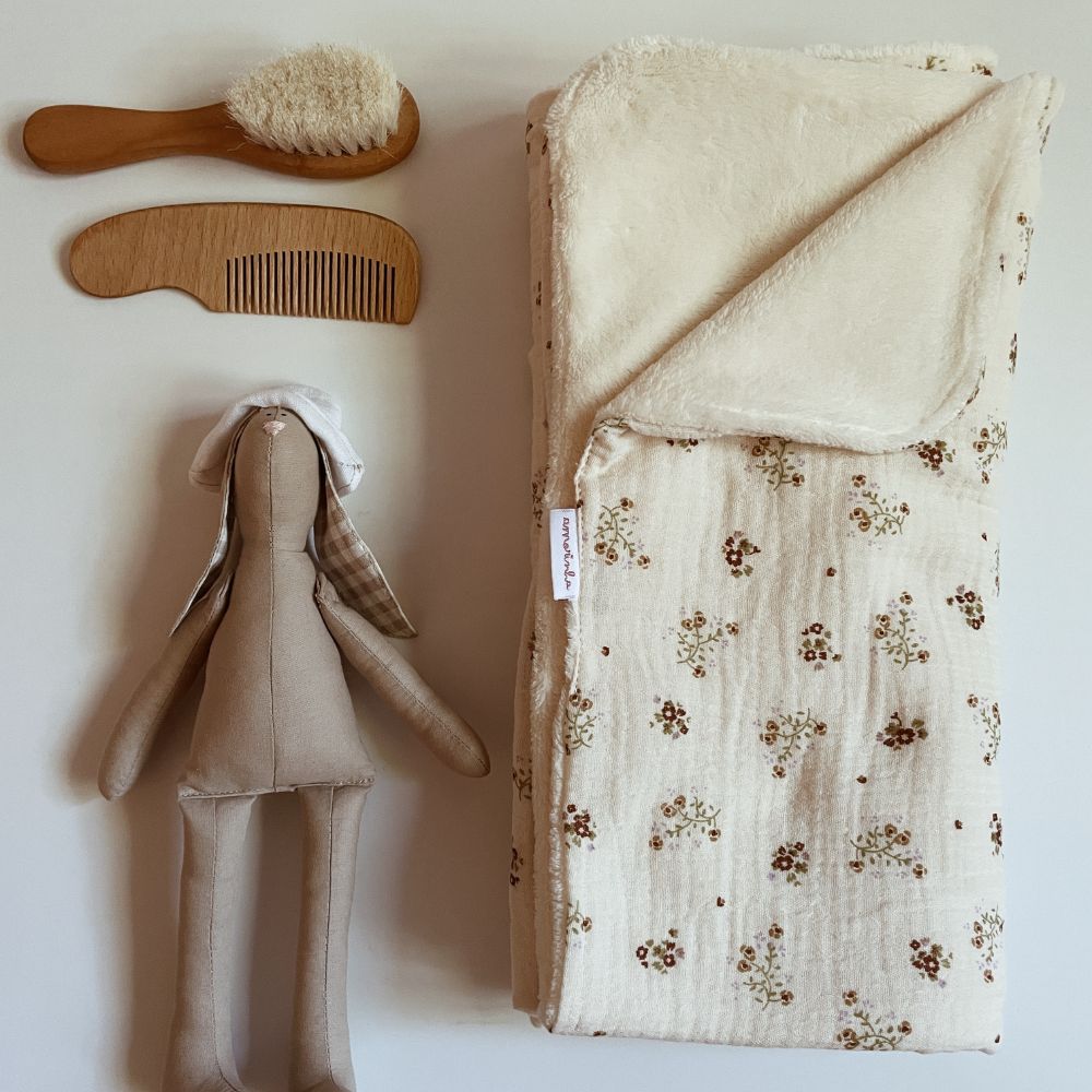 Escova e pente de madeira, manta floral e boneco de tecido para bebé.