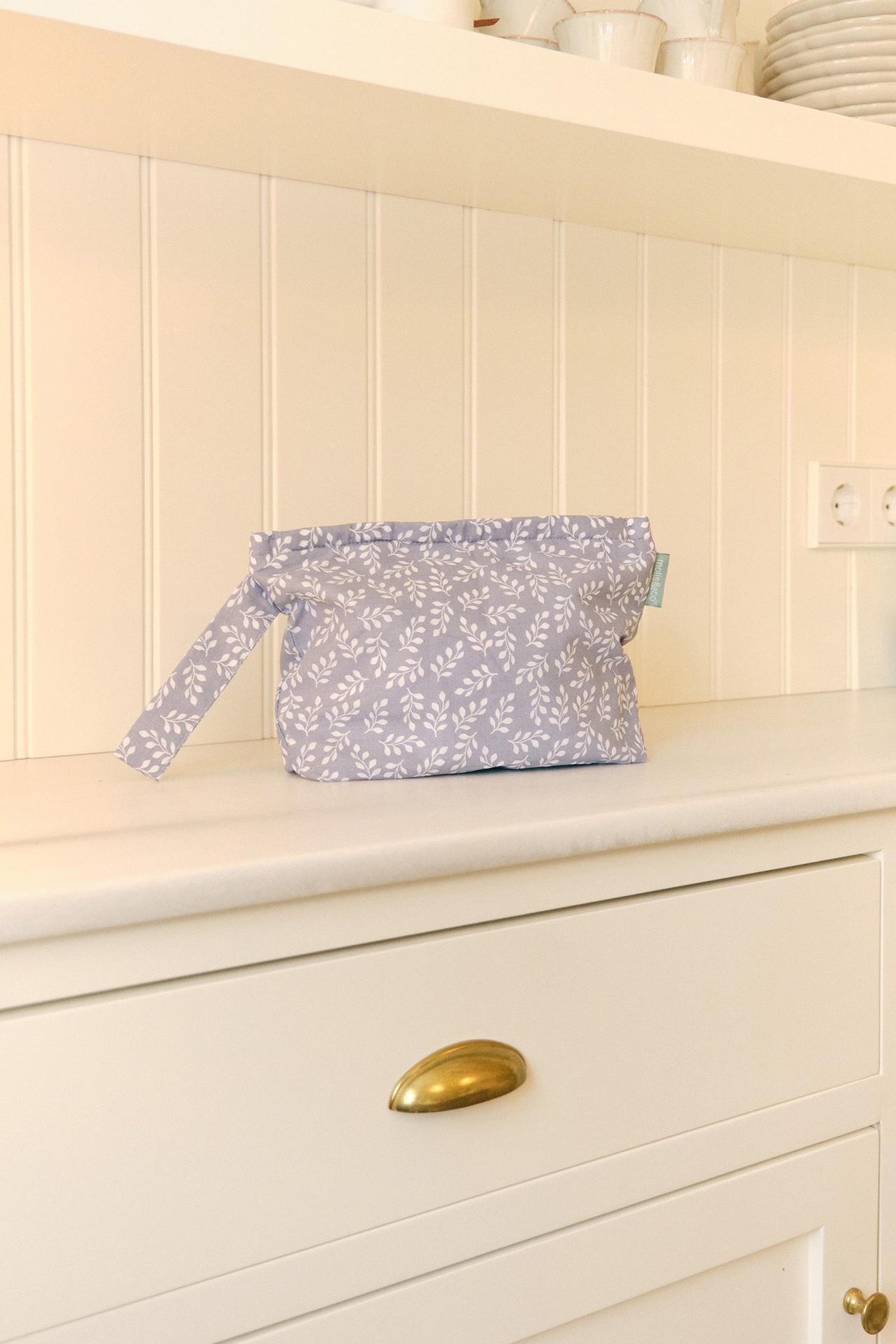 Necessaire cinzenta com padrão branco de folhas sobre superfície branca