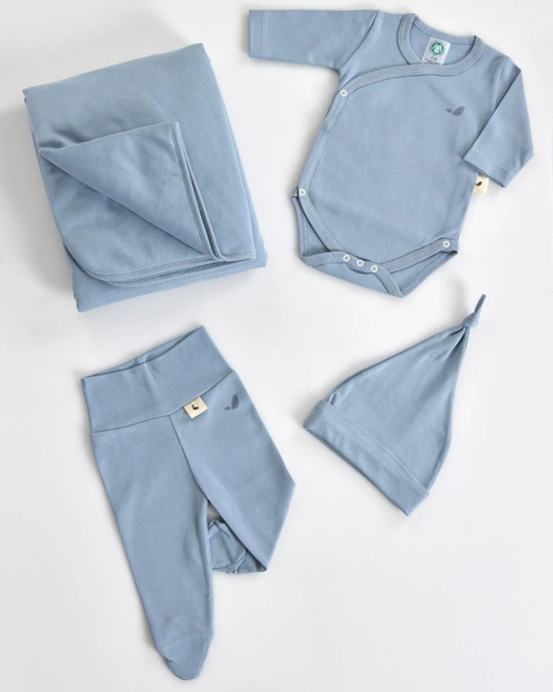 Conjunto de roupa de bebé azul claro com manta, body, calças e gorro.