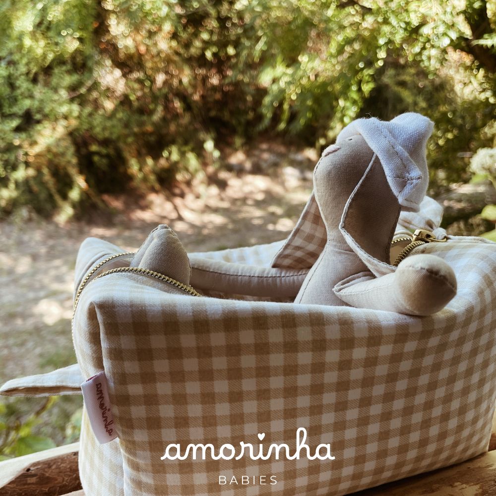 Cama de criança xadrez bege e branco com brinquedo coelho de tecido bege com chapéu