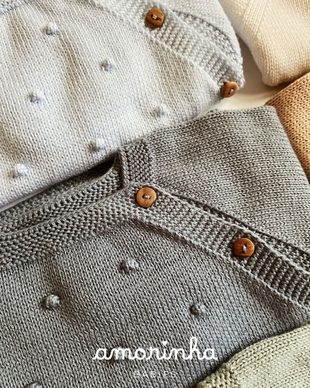 Roupas de bebé em malha com botões de madeira e detalhes em relevo