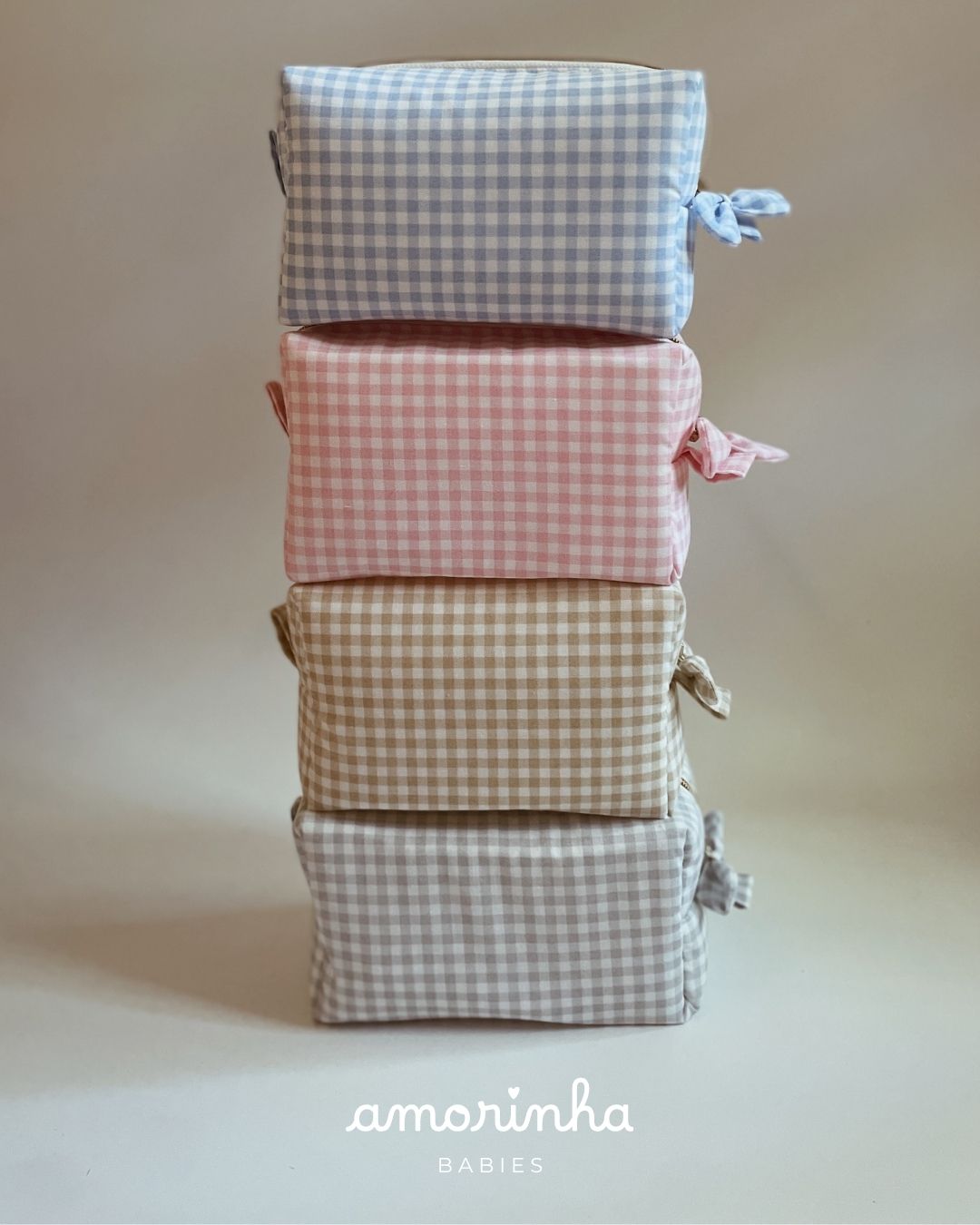 Quatro bolsas retangulares vichy em azul, rosa, bege e cinza empilhadas