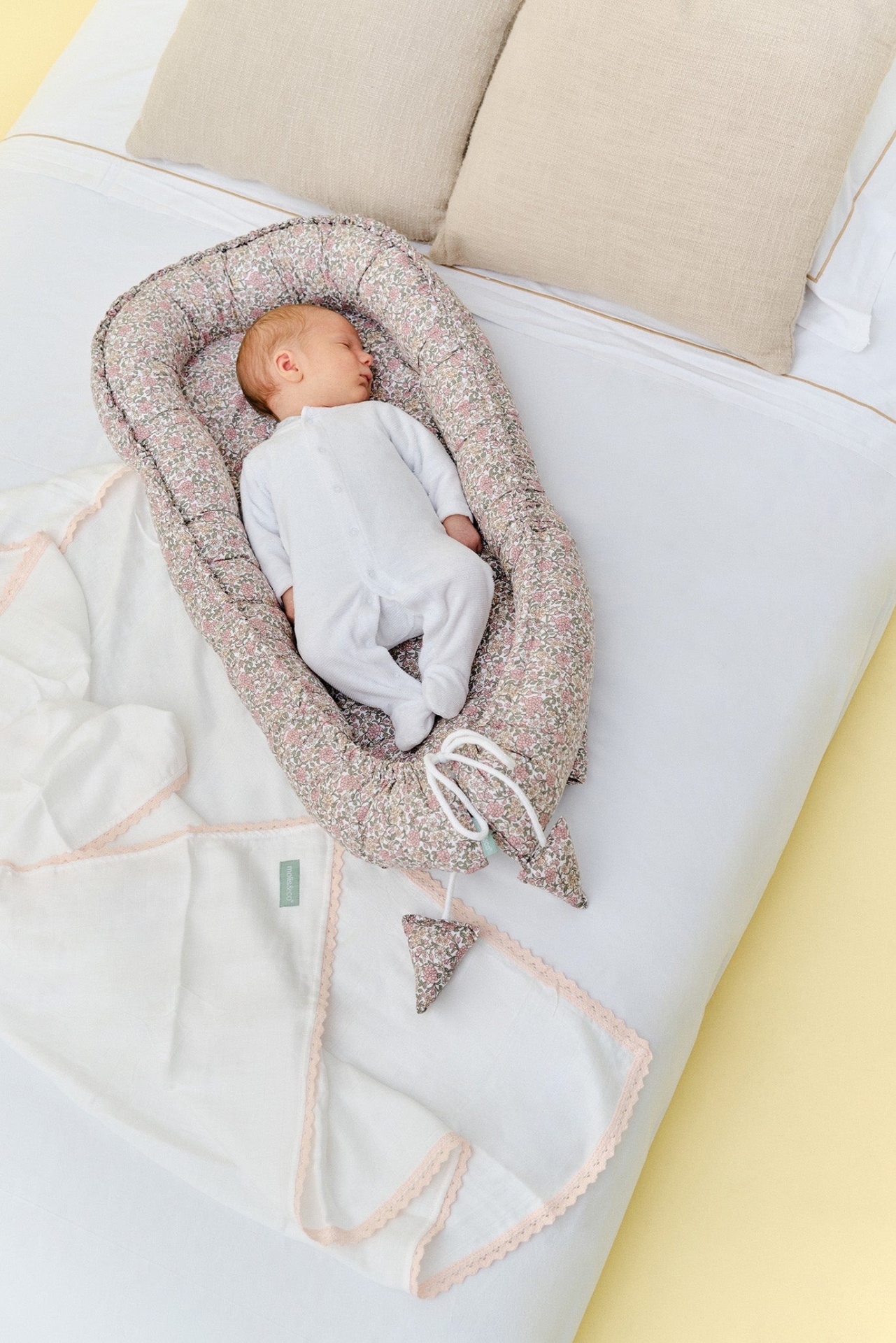 Ninho de bebé floreado em cama com bebé a dormir