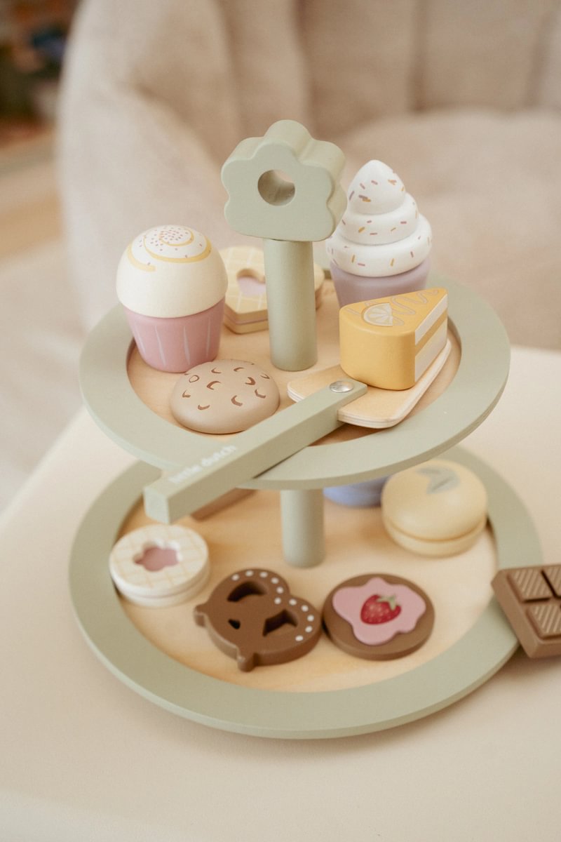 Suporte de madeira com brinquedos de bolos e bolachas de madeira em tons pastel
