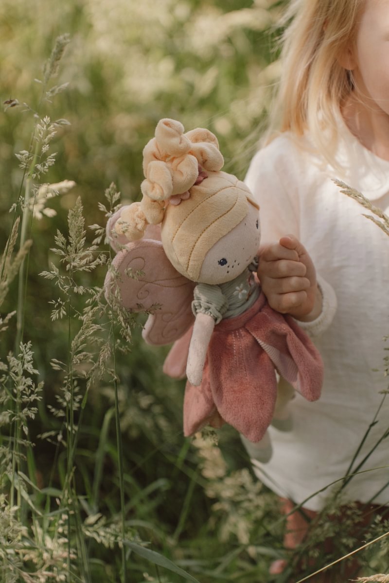 Boneca de peluche fada com vestido cor-de-rosa e verde na mão de criança