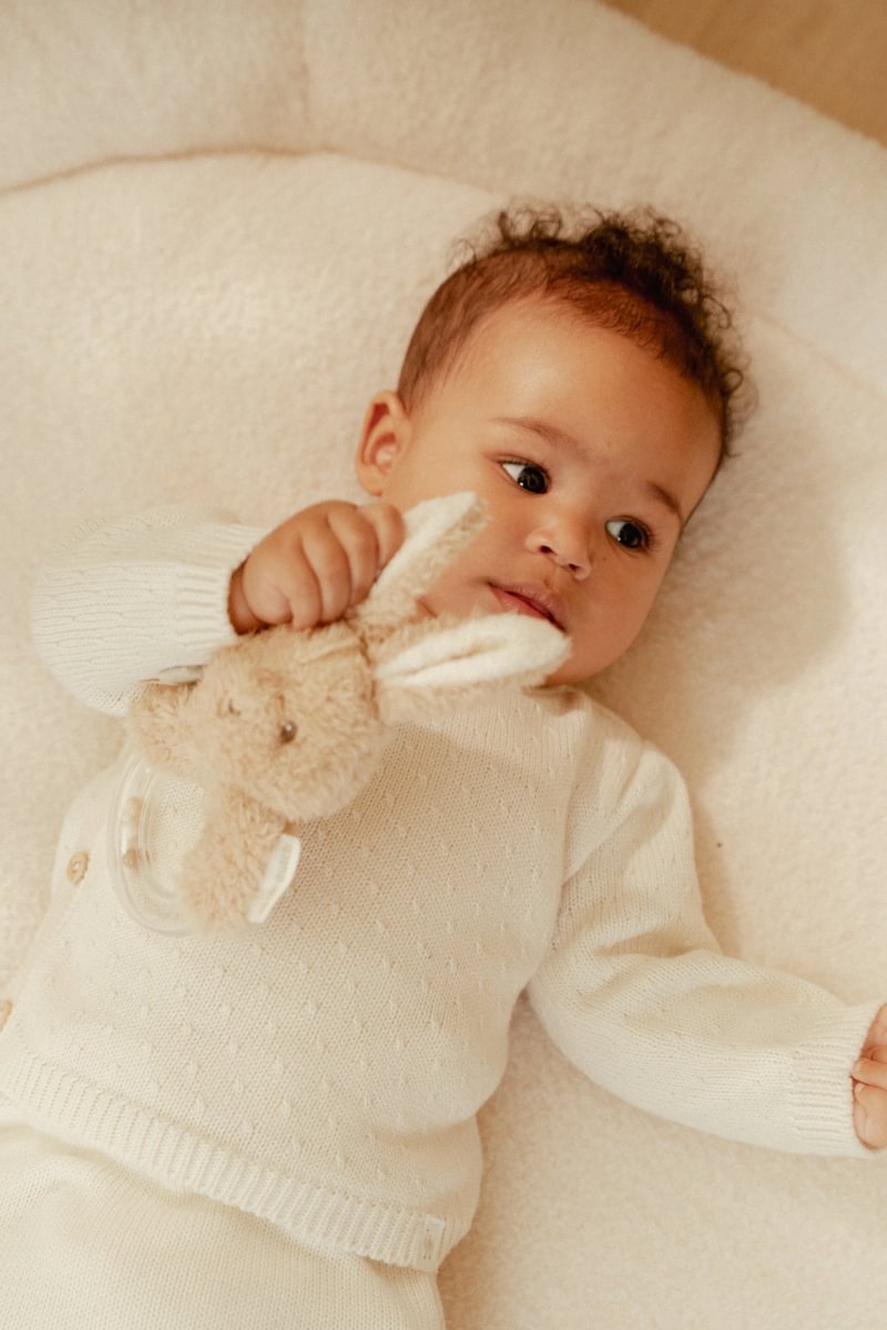 Bebé deitado com camisola branca e brinquedo de coelho macio