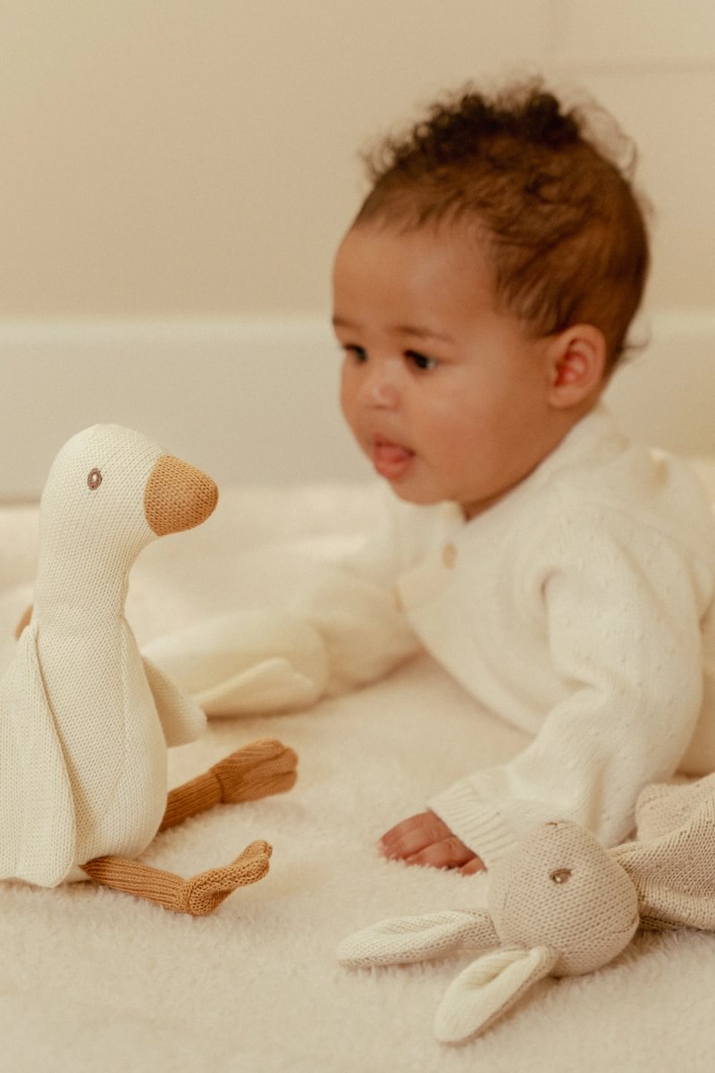 Bebé a brincar com peluches macios em tapete claro