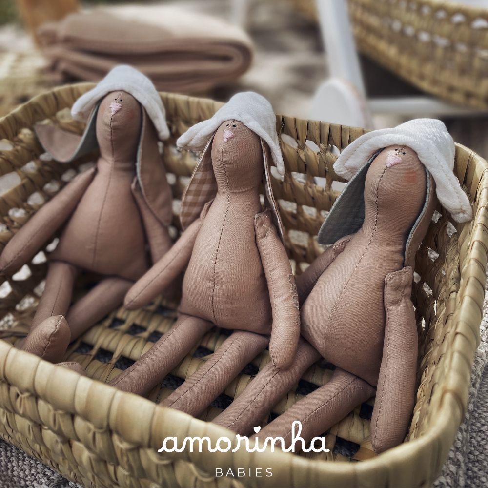 Três bonecos de tecido castanho em cesta de palha