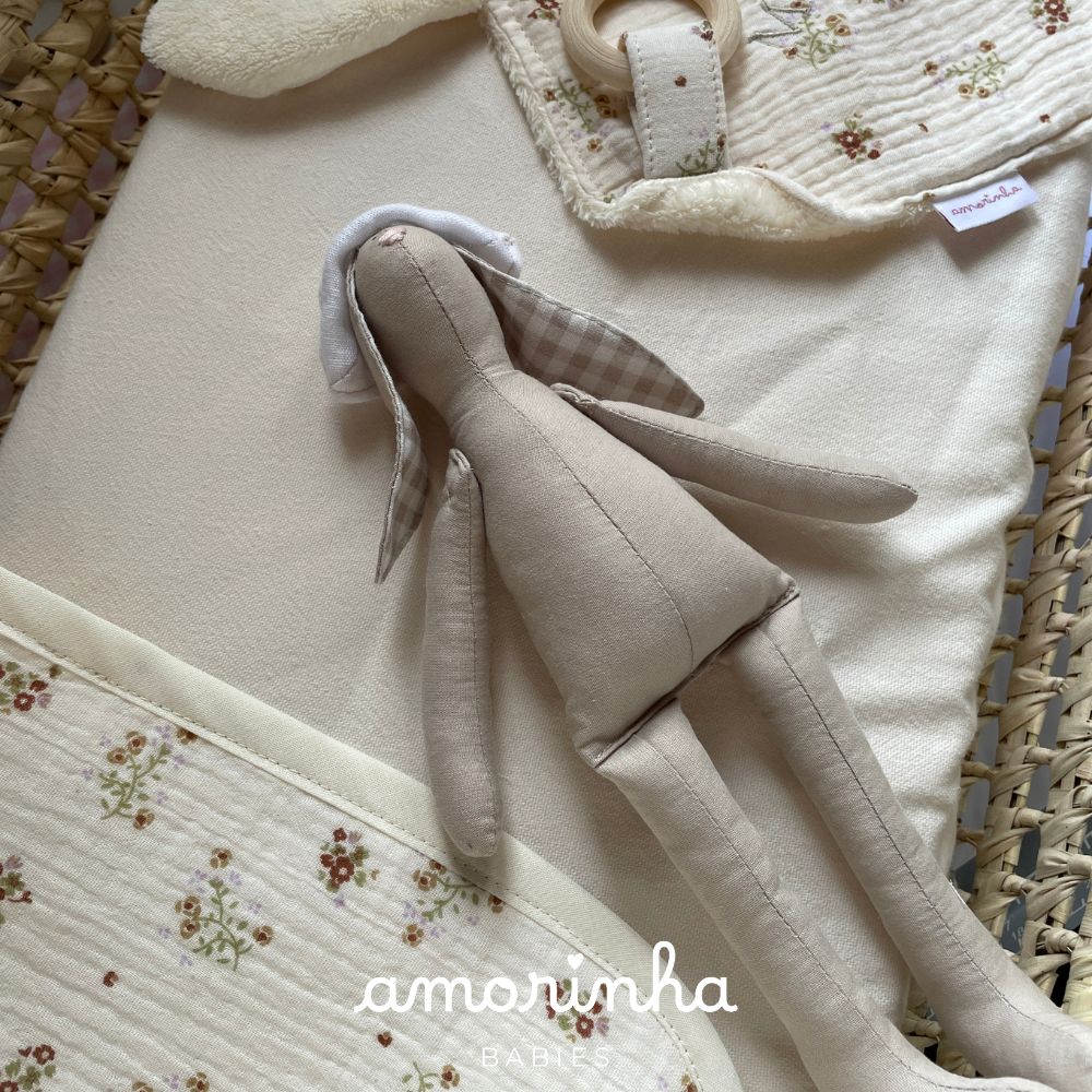 Boneco de tecido bege com roupa creme e padrão floral