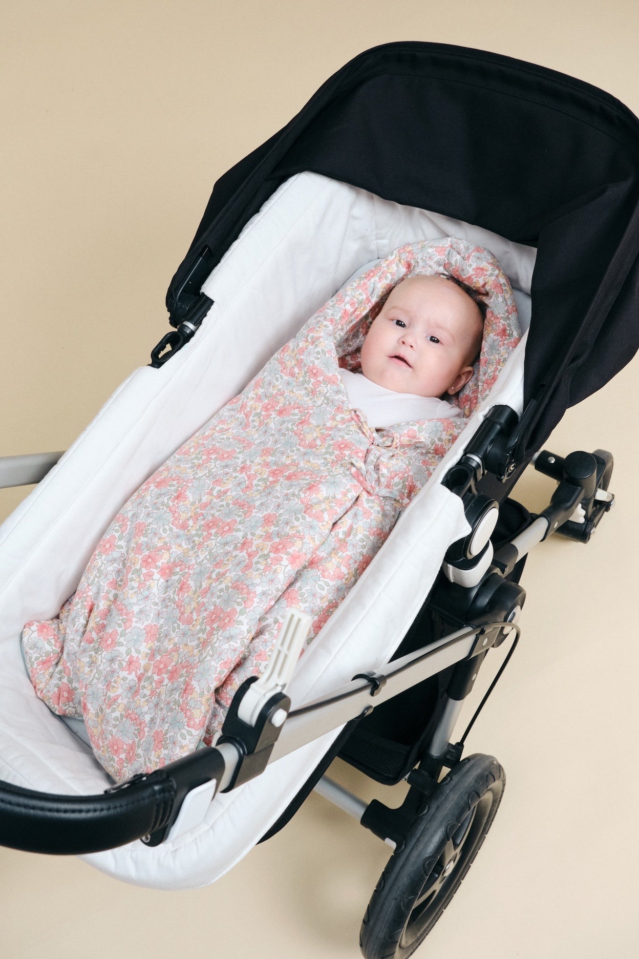 Bebé num carrinho com saco de dormir floral rosa e cinza