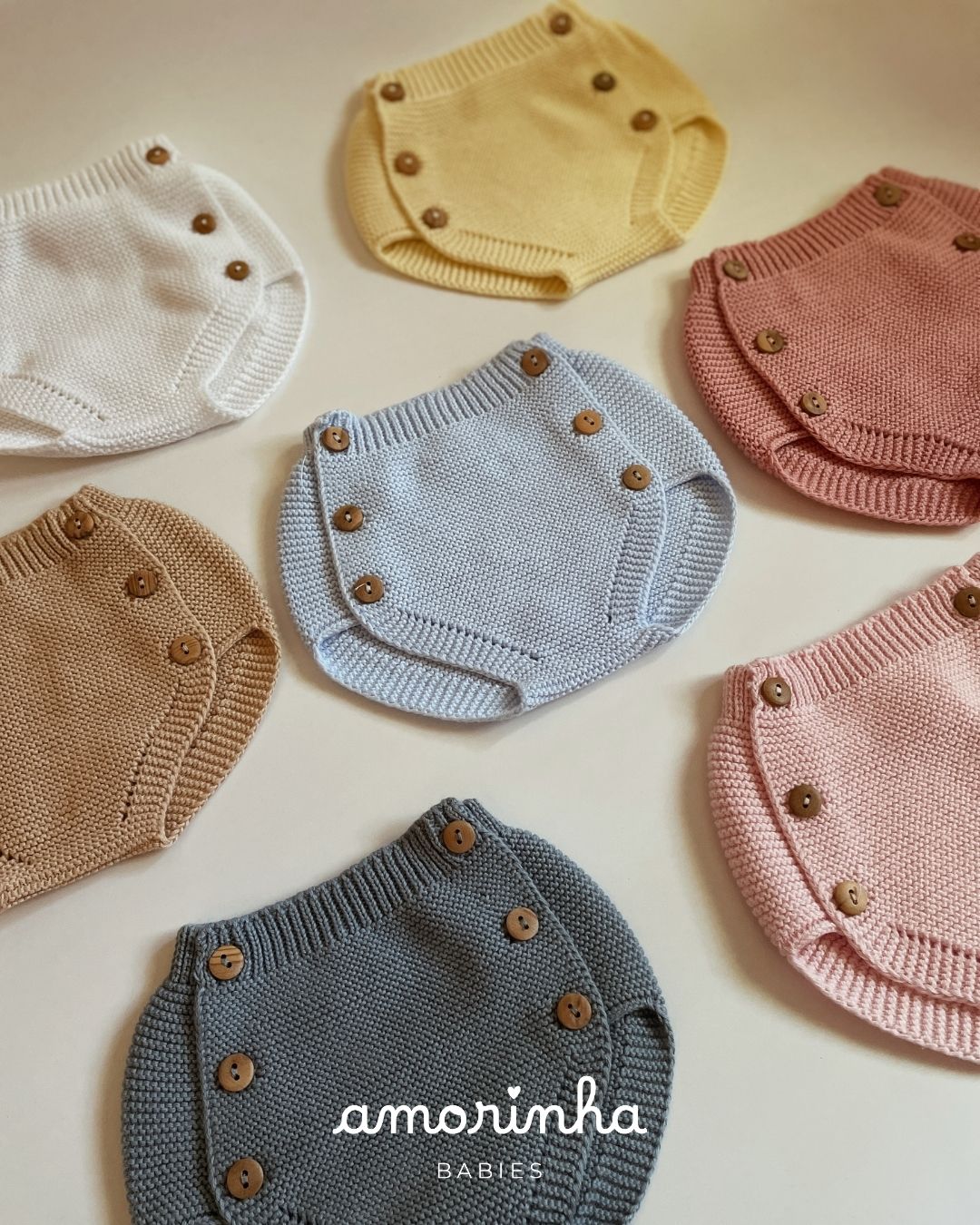 Fraldas de bebé em tricot de várias cores com botões de madeira