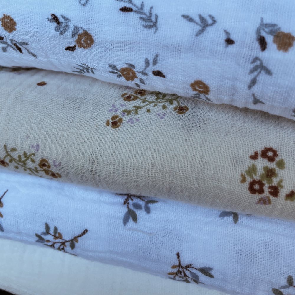 Tecidos de algodão com padrão floral em tons castanhos e verdes sobre fundos claros.