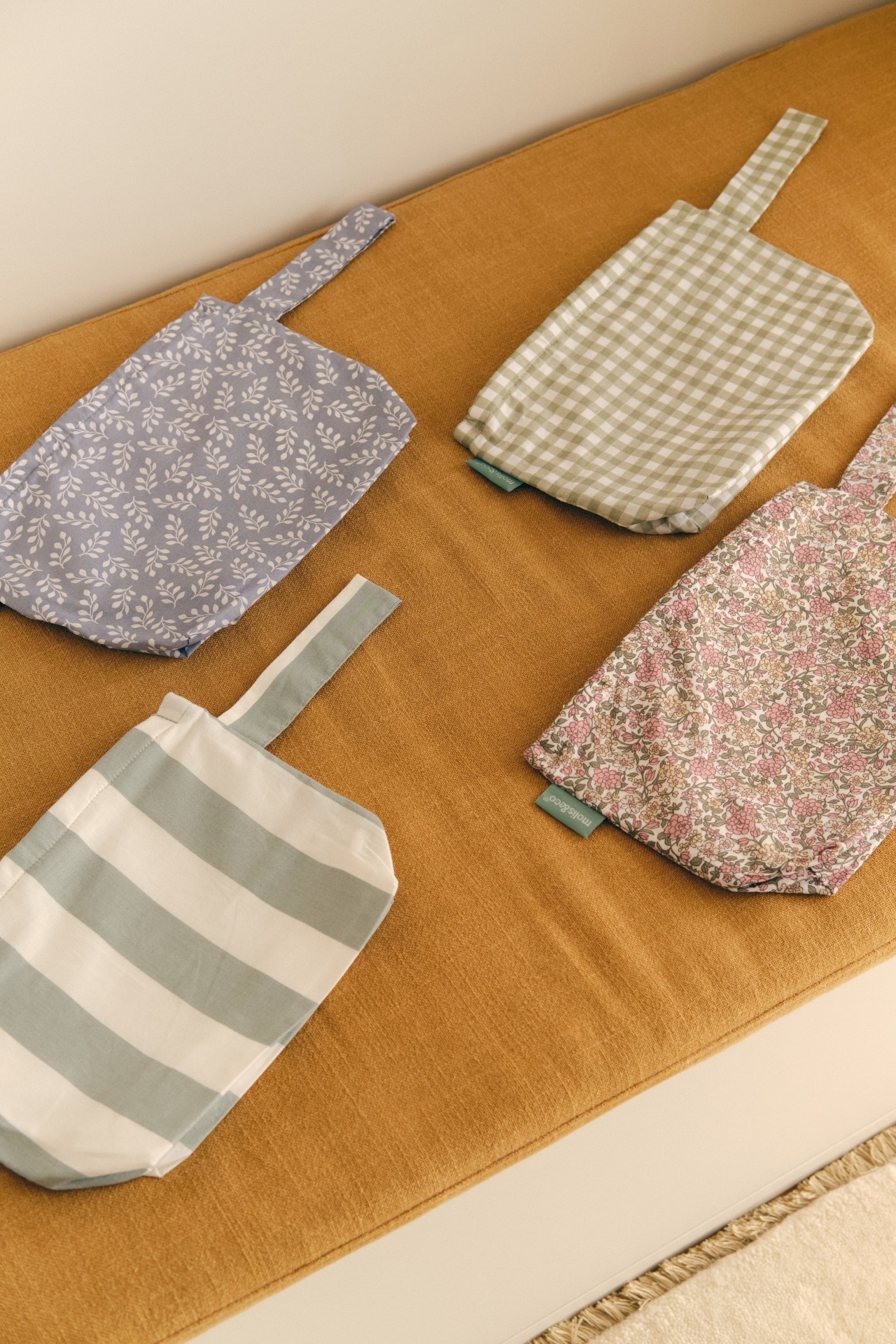 Quatro sacos de pano com diferentes padrões colocados sobre manta castanha