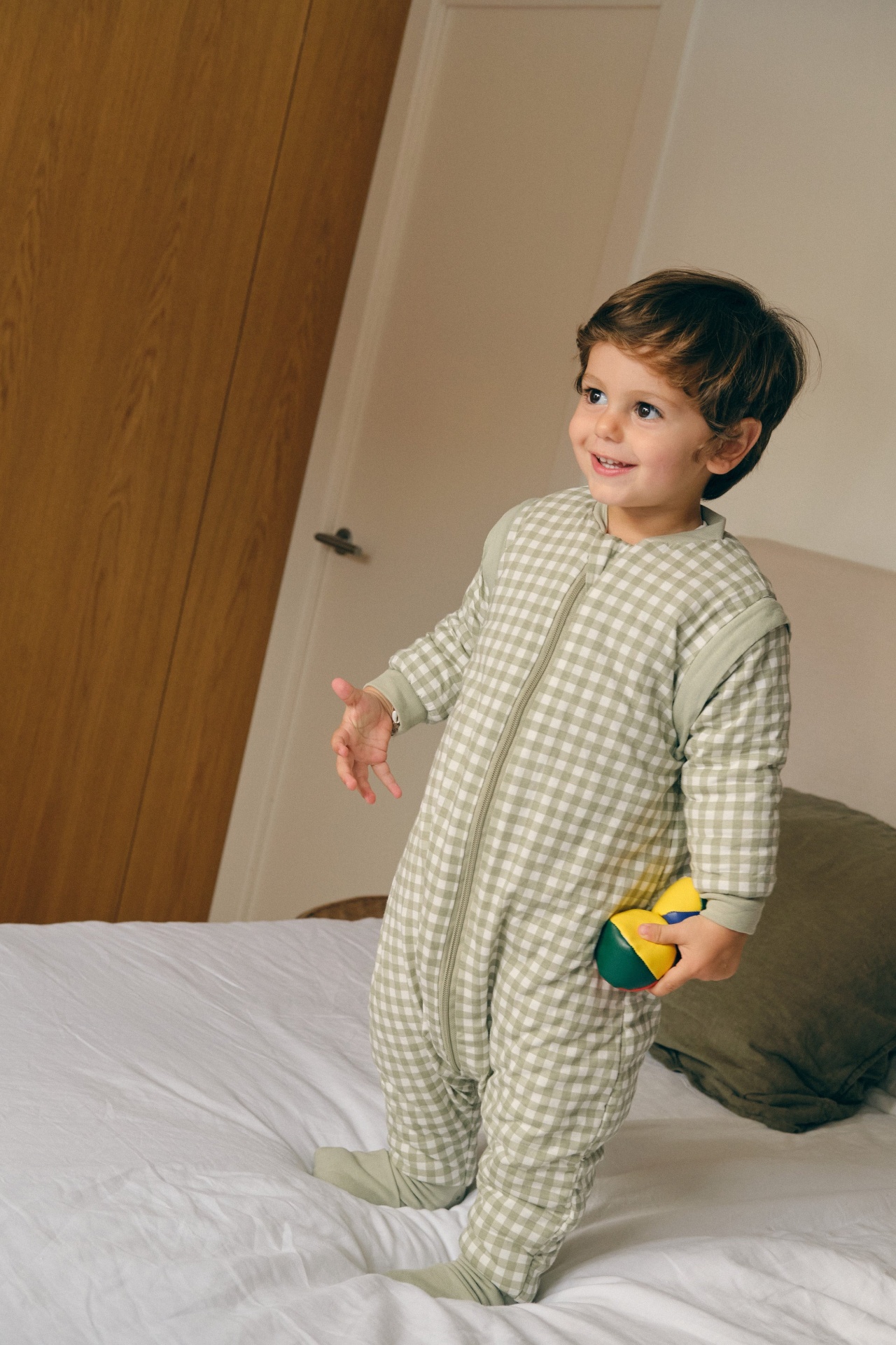 Criança vestindo pijama xadrez verde claro e creme em quarto