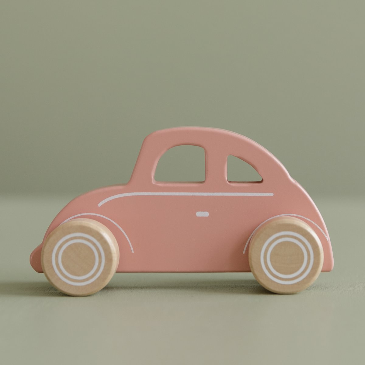 Brinquedo de madeira em forma de carro cor-de-rosa com rodas naturais e detalhes brancos