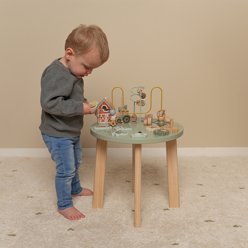 Criança a brincar com mesa de brinquedos educativos em madeira.