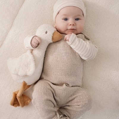 Bebé vestido de bege com peluche de pato branco.