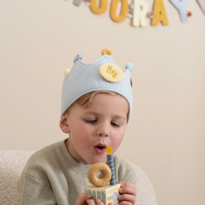 Criança com coroa azul e bolo de madeira com vela azul