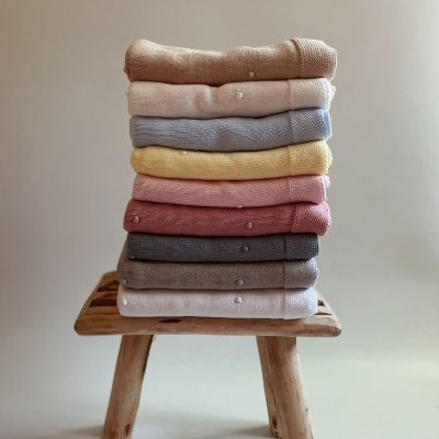 Conjunto de malhas coloridas empilhadas sobre banco de madeira