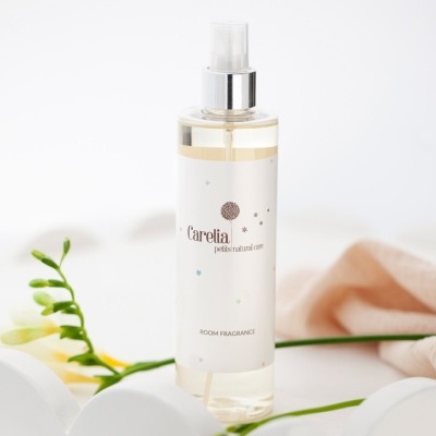 Frasco spray de fragrância para ambientes Carelia petits natural care com flor e tecido rosa ao fundo