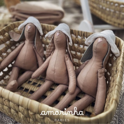 Três bonecos de tecido castanho em cesta de palha