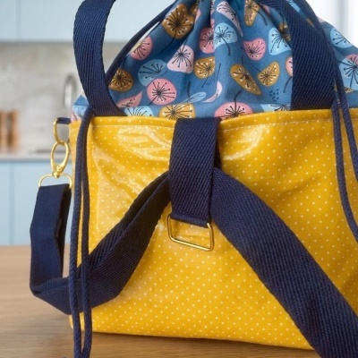 Mala de tecido amarelo com alças azuis e padrão floral interior