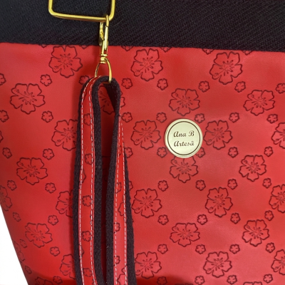 Bolsa vermelha com padrão floral e etiqueta Ana B Artesã