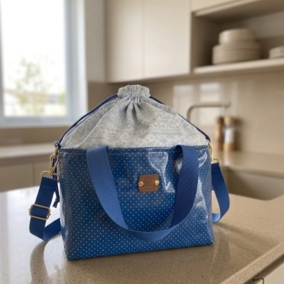 Mala azul com pontos brancos e tecido branco com padrão floral azul, sobre um balcão de cozinha.