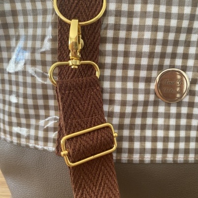 Bolsa com padrão xadrez castanho e branco e alça castanha com fivela dourada