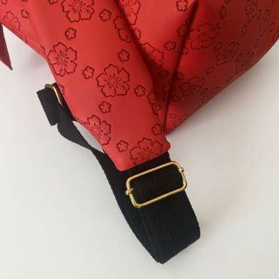 Bolsa vermelha com padrão de flores e alça preta com fivela dourada