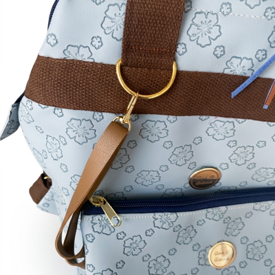 Mochila azul clara com padrão floral e detalhes castanhos