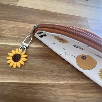 porta-moedas com padrão de girassóis e abelhas e chaveiro de girassol