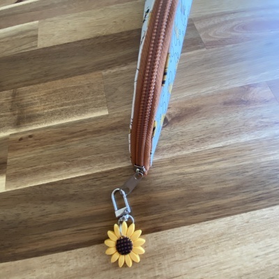Estojo com chaveiro de girassol amarelo em superfície de madeira