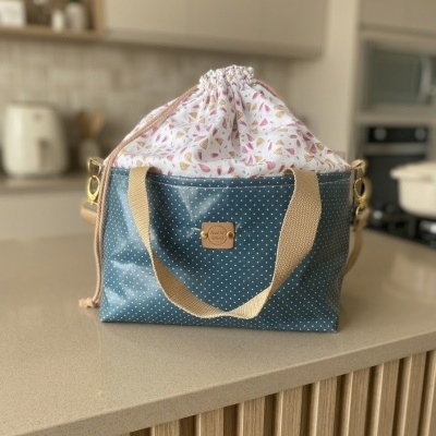 Bolsa tipo saco azul com bolinhas brancas e parte superior branca com padrão de folhas cor-de-rosa e amarelas.
