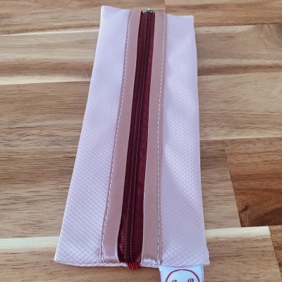 Estojo de tecido rosa com zíper bordô e etiqueta Ana B Artesã