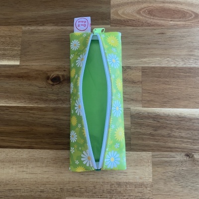 Estojo verde com flores e fecho éclair sobre mesa de madeira