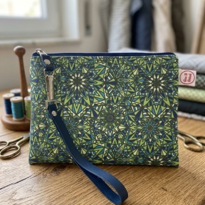 Carteira ou bolsa pequena com padrão geométrico em verde e azul, com fecho e alça azuis