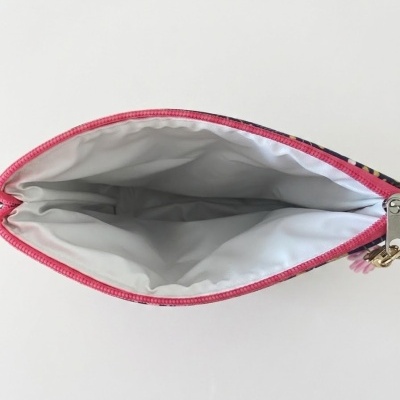 Bolsa tipo estojo aberta com interior branco e fecho rosa