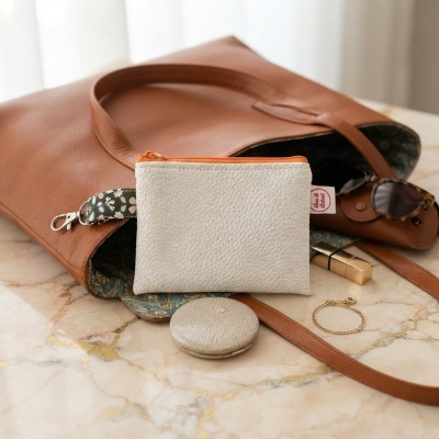 Bolsa castanha de couro com acessórios sobre mesa de mármore