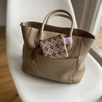 Mala de couro bege com bolsa pequena estampada com padrão castanho e etiqueta rosa