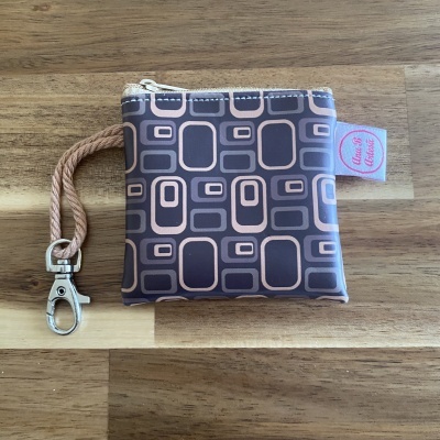 Carteira pequena em tecido castanho com padrão geométrico e fecho zipper