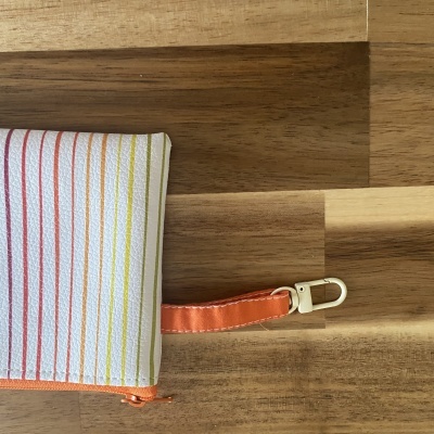 Necessaire com riscas coloridas verticais e alça laranja com mosquetão