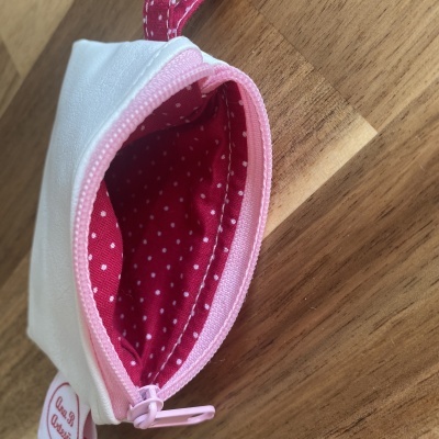 Mala pequena branca com interior rosa e pontos brancos