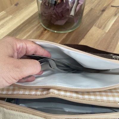 Bolsa com padrão xadrez castanho e bege com interior branco e talheres guardados